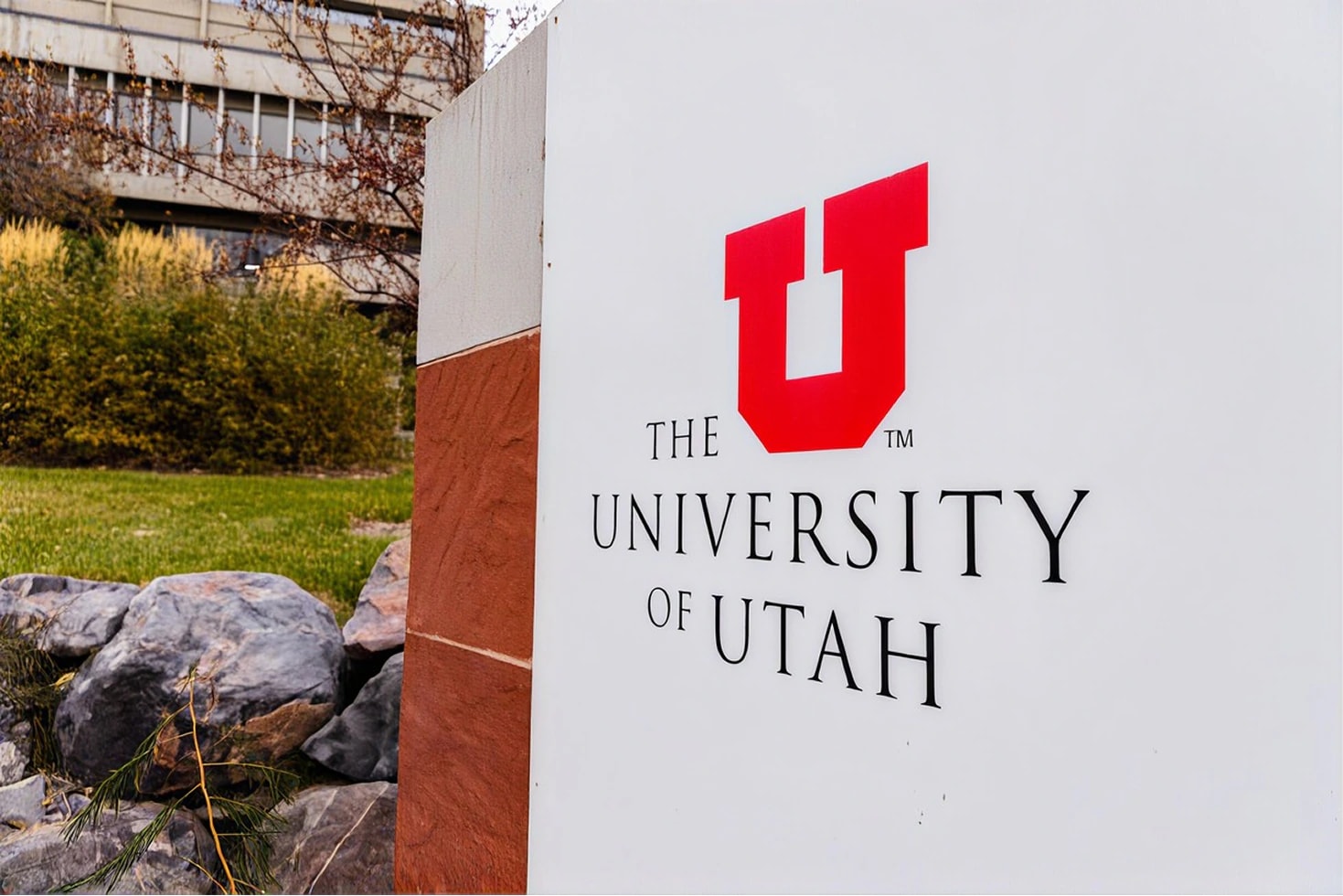 An entrance sign of the University of Utah on its campus, with the red block U above the name